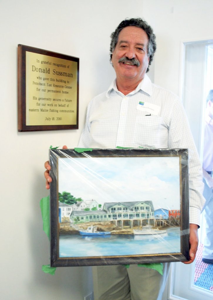 S. Donald Sussman shows off a painting of the new home for the Penobscot East Resource Center. Sussman received the painting as a gift after donating the restored waterfront building to the group.