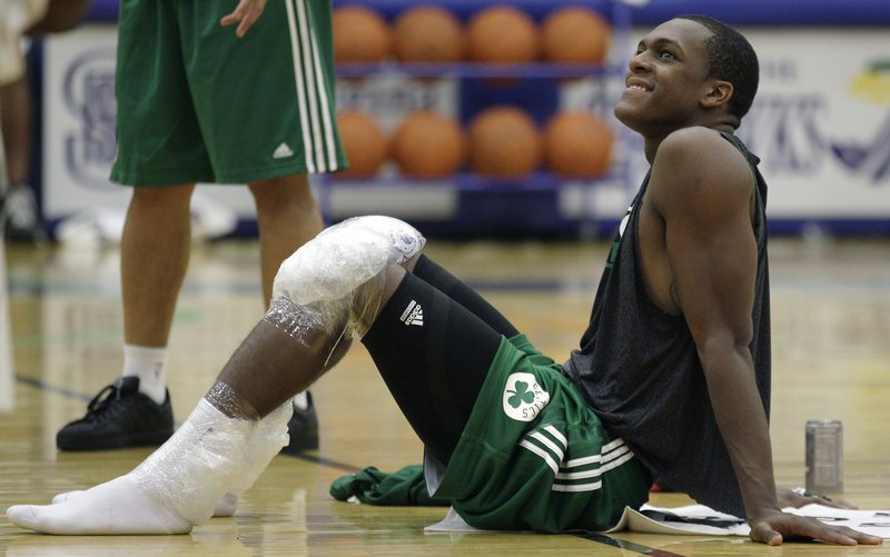 Celtics guard Rajon Rondo smiles as he rests on the court with his knees iced after their practice at the team’s training camp at Salve Regina University in Newport, R.I.