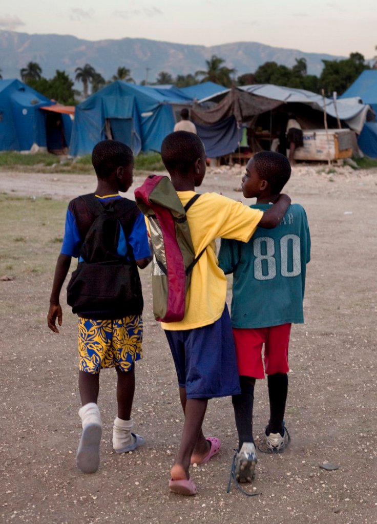Elisee Anderson, right, and his friends walk home earlier this month after soccer practice next to a refugee camp for people displaced by the earthquake at a sports complex in Port-au-Prince. On Friday, an isolated storm destroyed an estimated 8,000 tarps, tents and shacks in the capital and killed at least six people, including two children.