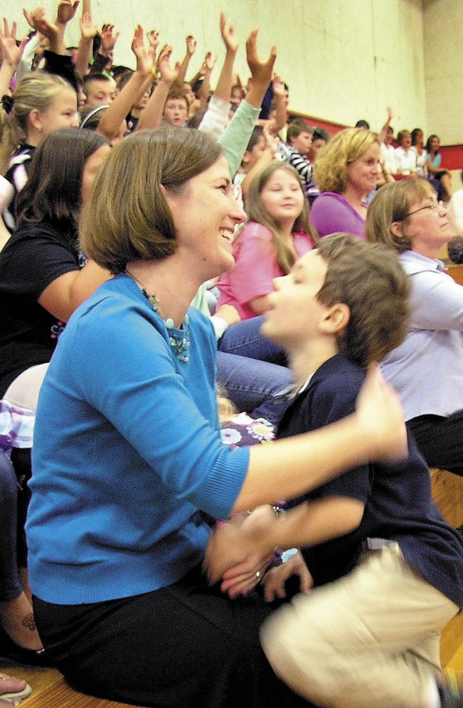 HELPING HANDS: Shelly Moody, a teacher at Williams Elementary School in Oakland, holds onto her 5-year-old son, Jacob, Friday morning as she is announced as the 2011 Maine Teacher of the Year. The school assembly was advertised as a gathering about anti-bullying to keep it a surprise. In the background, students, teachers and parents raised their hands when asked whether they thought the assembly was about something else.