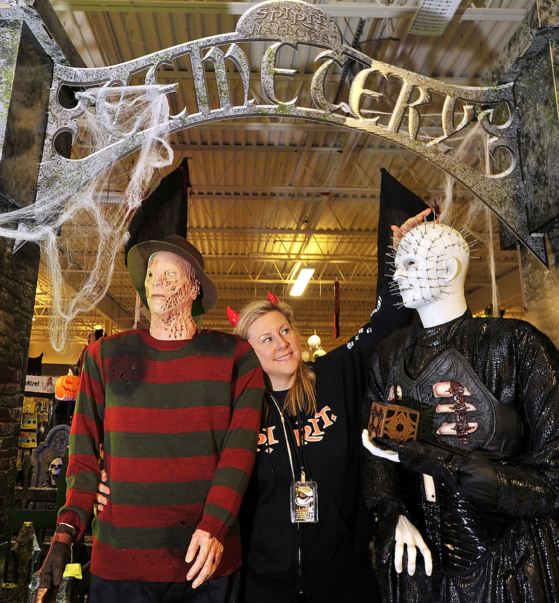 Retailer Deede Dunbar stands between costumes of Freddy Krueger and Pinhead at the Spirit Halloween store she owns in South Portland on Friday. “In Maine, we love Halloween,” she said.