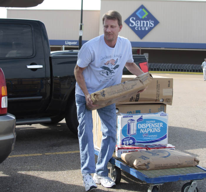 Bryan Daniels loads supplies into his SUV at Sam's Club in Jackson, Miss., recently. Economists think consumers will spend at a slightly slower pace through the rest of this year.