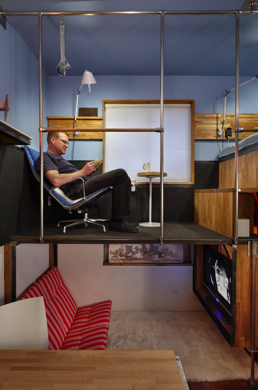 Steve Sauer relaxes in the cafe area of his 182-square-foot condo. "I was worried as I filled in all the upper spaces that it would feel cramped, but it didn't," he says. The window is at street level. The little table is Ikea. It has a glass top that swivels open, providing storage.