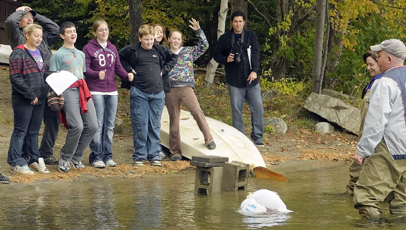 China Middle School students cheer as their boat finally sinks after Jobs For Maine’s Graduates Chief Operating Officer Craig Larrabee, far right, put another brick on top of it on Wednesday morning. Their boat was made from a plastic bag, a round pool noodle, milk jugs and twigs — part of the junkyard regatta portion of a training program at the YMCA Camp of Maine in Winthrop.