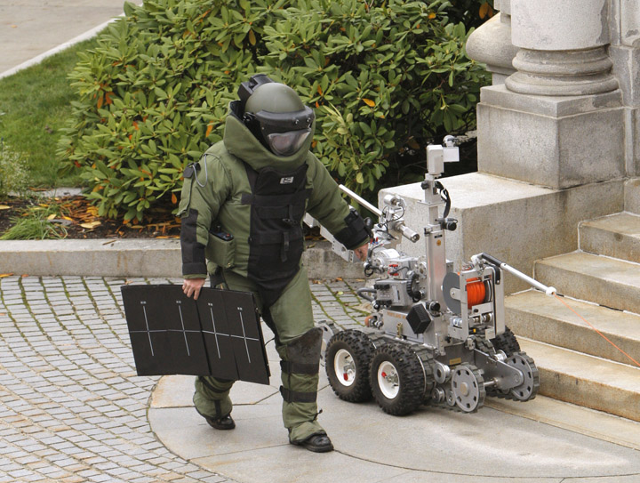Portland police bomb specialist Jay Twomey carries a piece of X-ray equipment away from a bush by the Edward T. Gignoux United States Courthouse where a suspicious package was spotted early this morning.