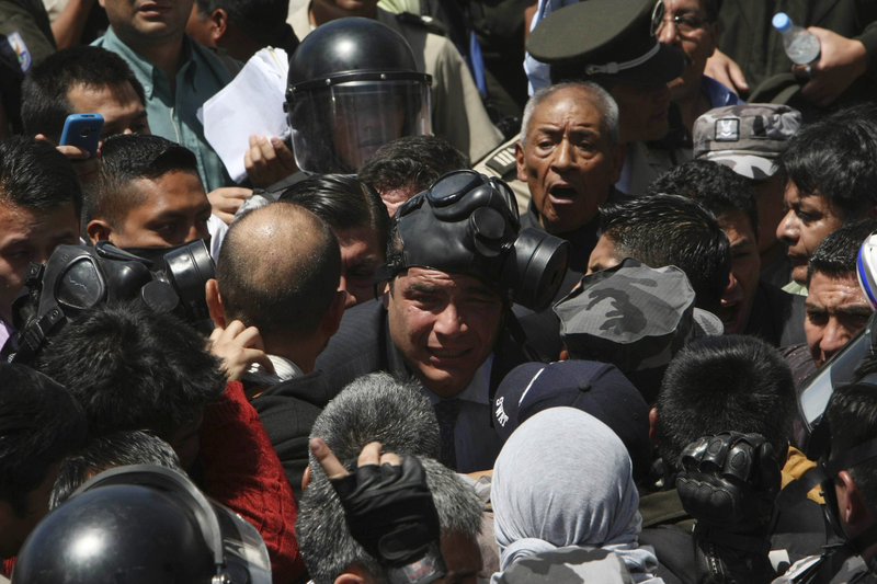 Ecuadorean President Rafael Correa, center, wearing a gas mask, is caught in a police protest Thursday at a barracks in the capital of Quito. The government declared a state of siege after rebellious police left Quito and other major cities unprotected in a nationwide strike. Looting was reported in the capital and two banks were sacked.