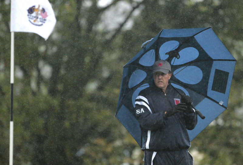 Phil Mickelson takes shelter under an umbrella Friday, when heavy rains soaked the course and forced suspension of play for more than seven hours at the Ryder Cup. As a result, none of the early fourball matches was completed.