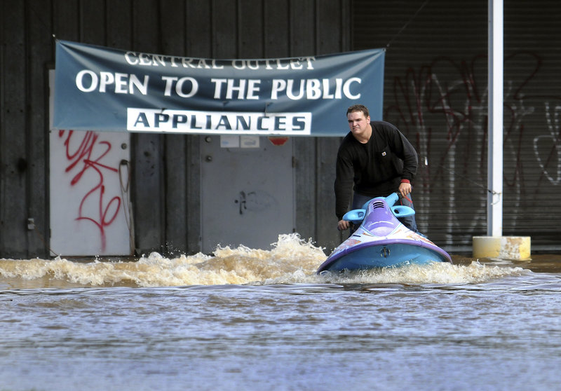 Matt Mitsdarfer rides his personal watercraft in a flooded Stanton, Del., parking lot Friday. Parts of the East Coast got up to 6 inches of rain in hours from a storm that was blamed for five deaths in North Carolina and one in Pennsylvania.