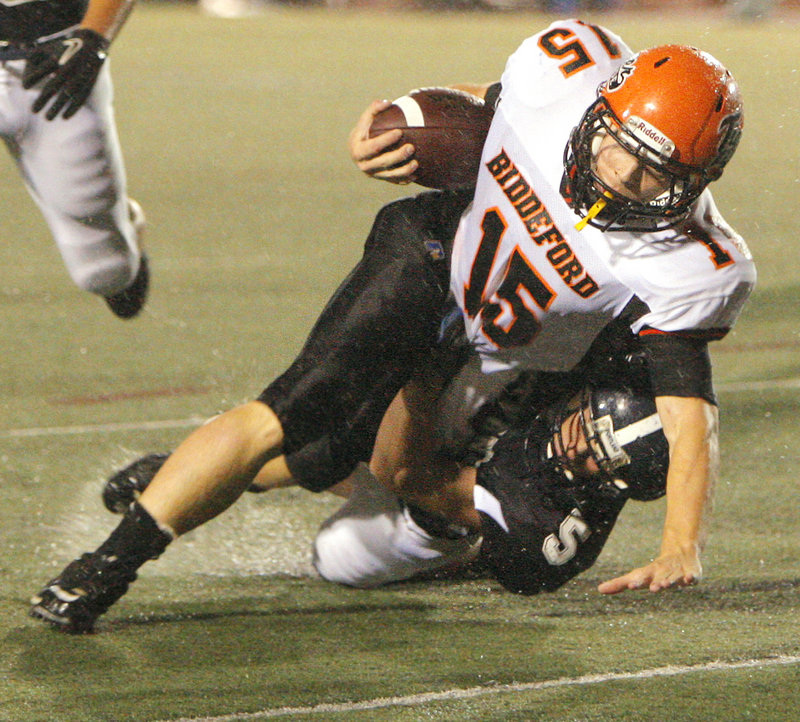 Biddeford quarterback Tyler Audie strains for balance Friday night while being brought down by Gary MacDonald of Portland. Audie sparked the Tigers to a 35-7 victory at Fitzpatrick Stadium.