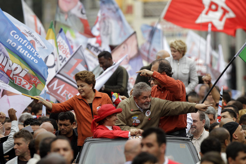 From the top of a vehicle, President Luiz Inacio Lula da Silva, right, Workers Party presidential candidate Dilma Rousseff, left, and first lady Marisa Leticia, bottom, wearing a red hat, greet supporters during a campaign rally in Sao Bernardo do Campo, Sao Paulo state, Brazil, on Saturday. Brazil will hold general elections today.