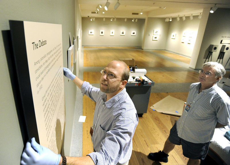 Ray Routhier, left, hangs a panel at the Portland Museum of Art under the direction of preparator Greg Welch as Welch sets up a photography exhibit. Welch has held this job for 35 years.