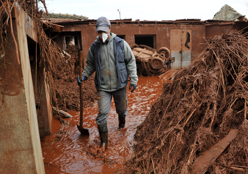 A villager walks through his yard flooded by toxic mud in Kolontar, Hungary, on Tuesday. At least four people have died in flooding caused by the rupture of a red sludge reservoir at an alumina plant in western Hungary.