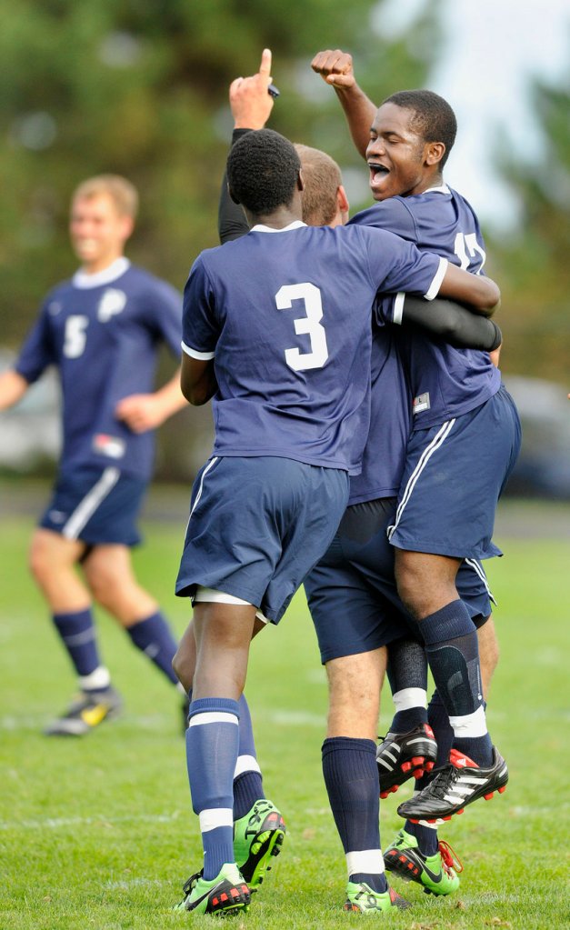 Ralph Houanche, right, of Portland celebrates with Abde Ahmed, 3, and another teammate after scoring in the first half of a game Tuesday against Cheverus. The goal stood up for a 1-0 victory.
