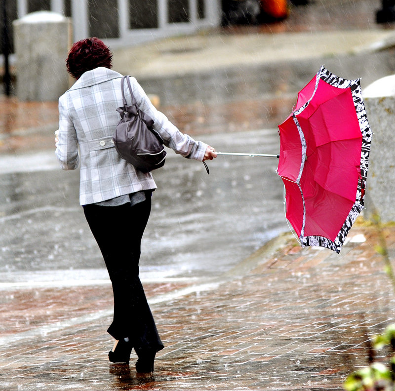 Amy Baum of Waterboro hangs on to her inside-out umbrella as she crosses Free Street in Portland on Wednesday. A soaking rain and gusting winds invaded Maine as a storm system made its way north.