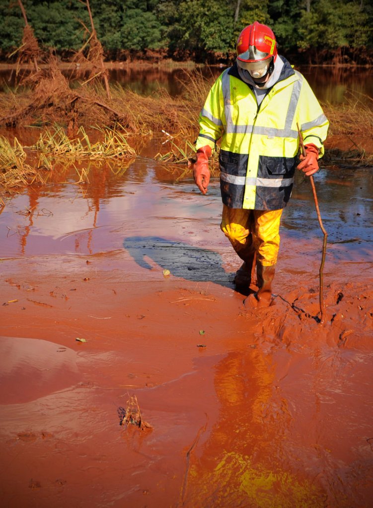 A Hungarian firefighter wades through toxic red sludge that burst out of a Hungarian factory’s reservoir and inundated three villages before reaching the Danube River on Thursday.