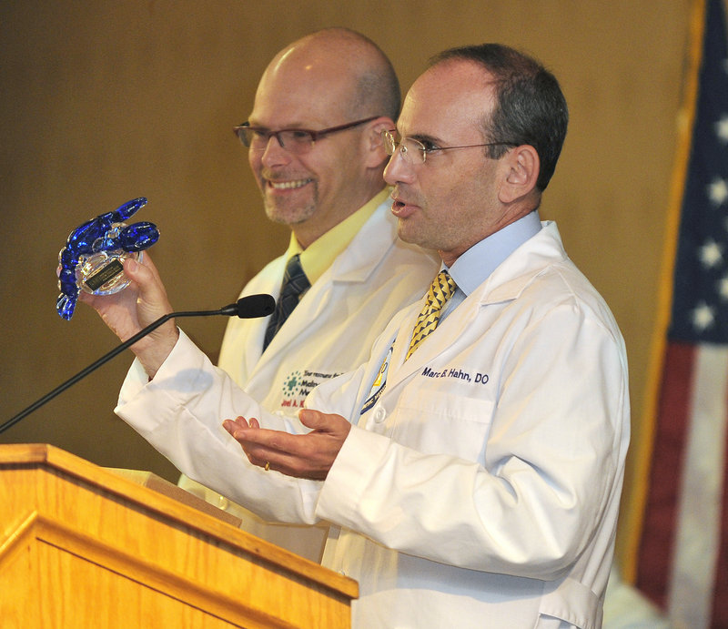 Dr. Marc Hahn, dean and senior vice president for health affairs, holds a blue glass lobster he is presenting to Dr. Joe Kase, president of Maine Osteopathic Association because “he is one in two million,” said Kase.