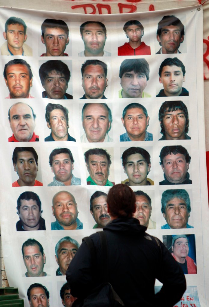 A journalist looks at a banner Friday with images of the 33 trapped men at the San Jose Mine in Copiapo, Chile.