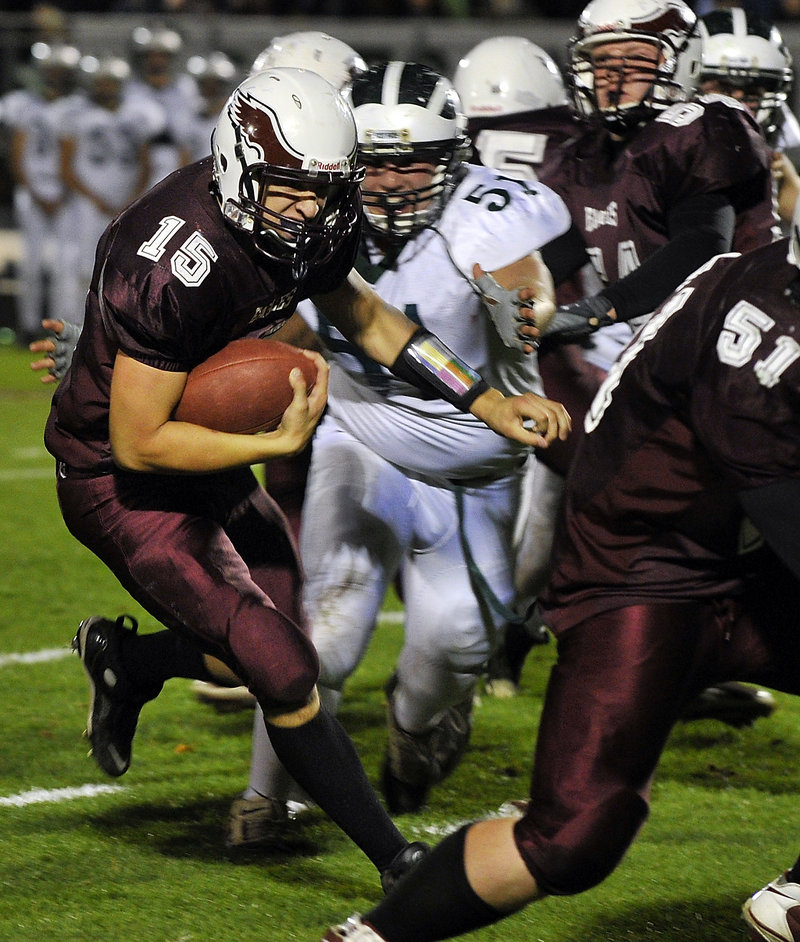 Cody Laberge of Windham follows lead blocker Shawn Francoeur while Bonny Eagle’s Nick Cawood moves in Friday night during a Class A football game at Windham. Bonny Eagle won, 21-19.