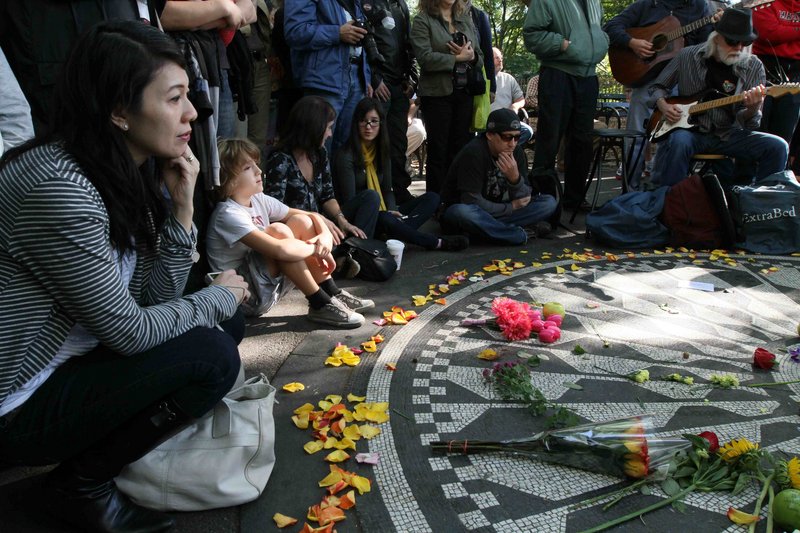 Janice Tong, left, of Sydney joins fans paying tribute to John Lennon on Saturday in New York’s Central Park. “I think the mourning is over for John,” said his ex-wife, Cynthia, in England. “I think it’s time to celebrate.”