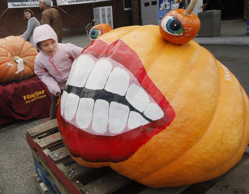 Rebecca Packard, 8, of Durham takes a look at a pumpkin decorated by Hannah Boone.