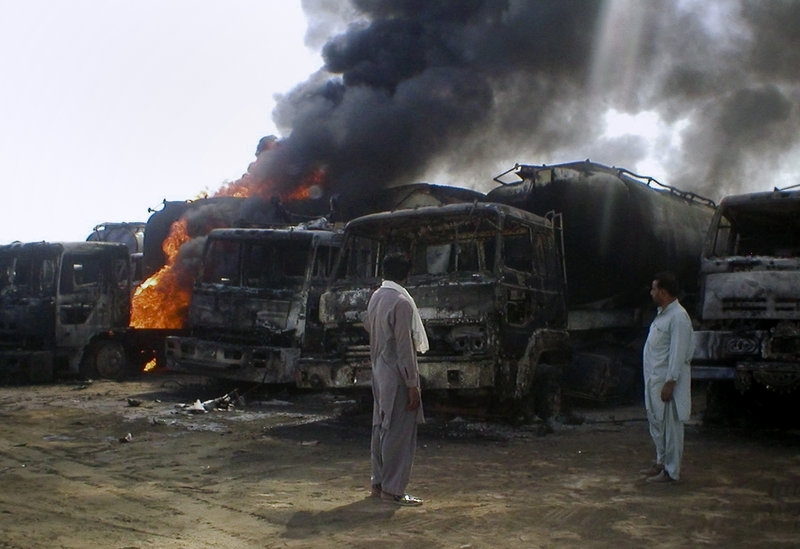 Local residents look at burning oil tankers after a militant attack in Mithri, about 120 miles east of Quetta, Pakistan, on Saturday. Gunmen armed with a rocket torched 29 NATO oil tankers in southwestern Pakistan before dawn Saturday.