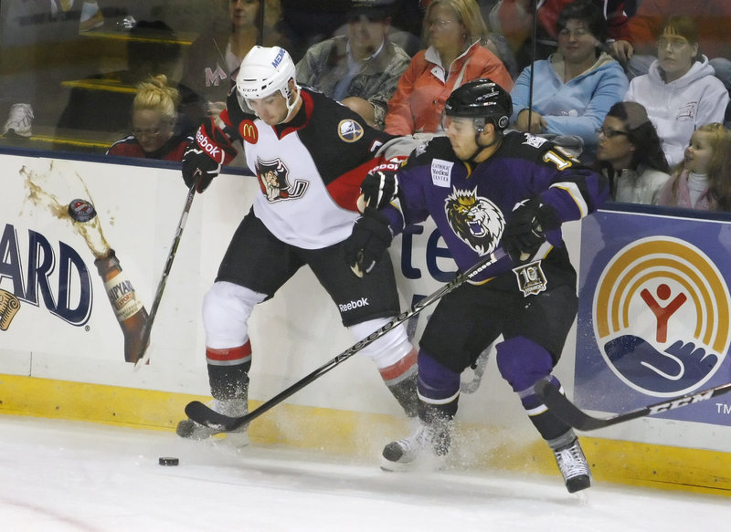 T.J. Brennan, left, of the Portland Pirates competes for the puck along the boards with Felix Schutz of the Manchester Monarchs during the first period of Portland’s 6-5 victory. The American Hockey League season opened Saturday night.
