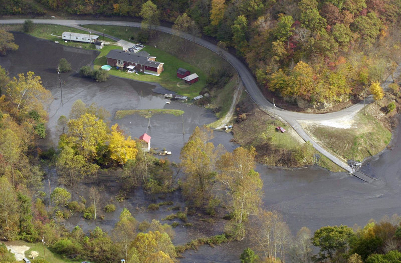 In this Oct. 16, 2000, photo, houses at Coldwater Fork sit along some of the 300 million gallons of coal slurry that spilled from a 68-acre retention pond upstream after the bottom fell out several days earlier, blackening 100 miles of waterways.