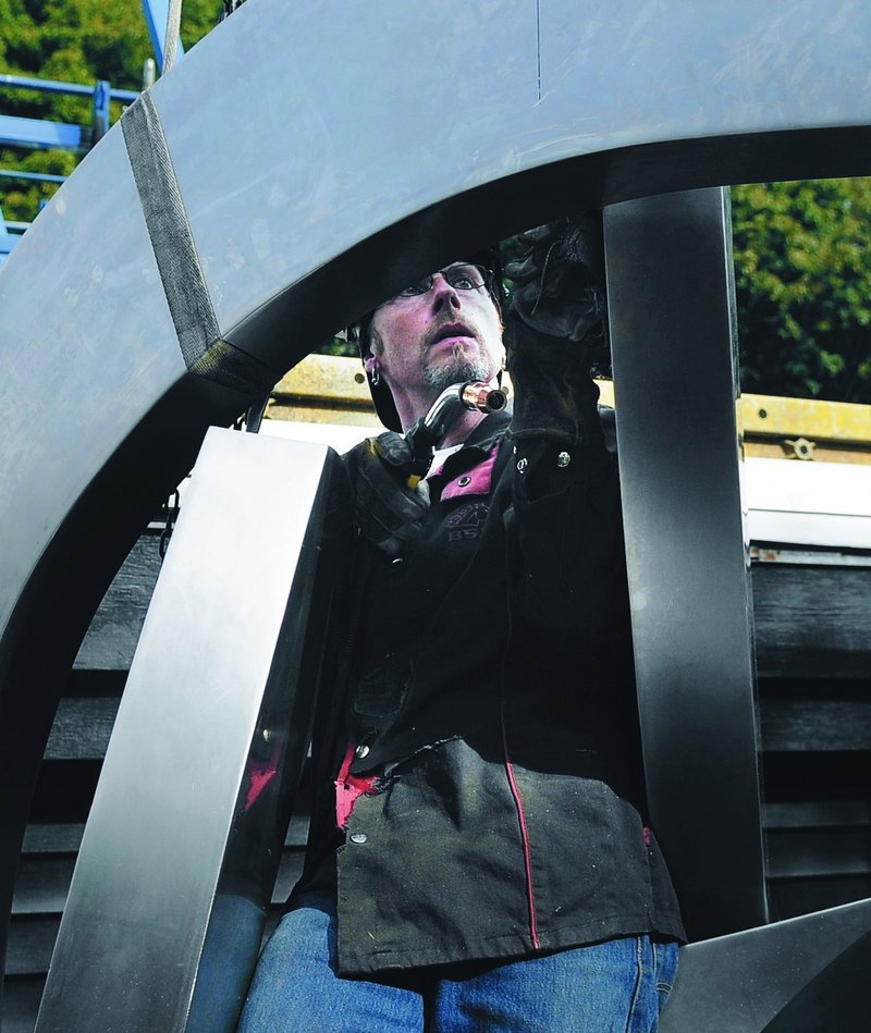 Robert Lash inspects a seam he welded near the top of the “Rising” sculpture at his studio and home in Gardiner.