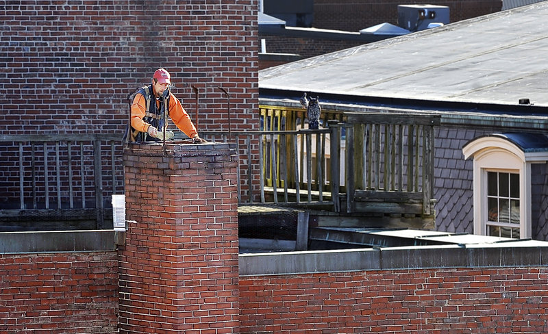 Scott Cook, a mason for South Portland-based Team Masonry, works in the sun as he repoints an old chimney on the roof of a building on Free Street on Tuesday. It should remain sunny and in the upper 50s today and Thursday before taking a rainy turn Friday and Saturday.