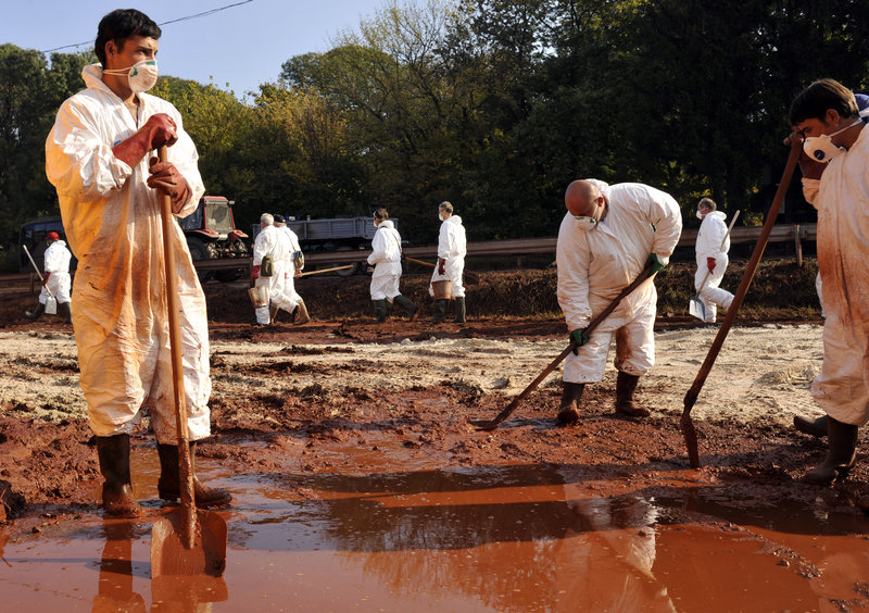 Volunteers wearing protective clothing clean toxic sludge Wednesday in Devecser, Hungary. “Life won’t be returning to normal for a very, very long time,” says Mayor Tamas Toldi.
