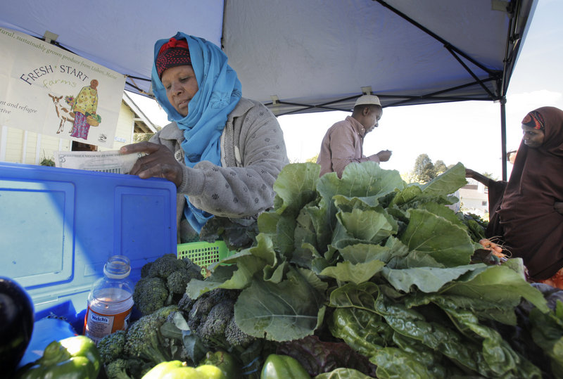 Seynab Ali, left, and Mohammed Abukar sell produce Wednesday at the community garden on Boyd Street in Portland. The two sell vegetables they grow as part of a farmer’s collective called Fresh Start Farms at a farm in Lisbon.