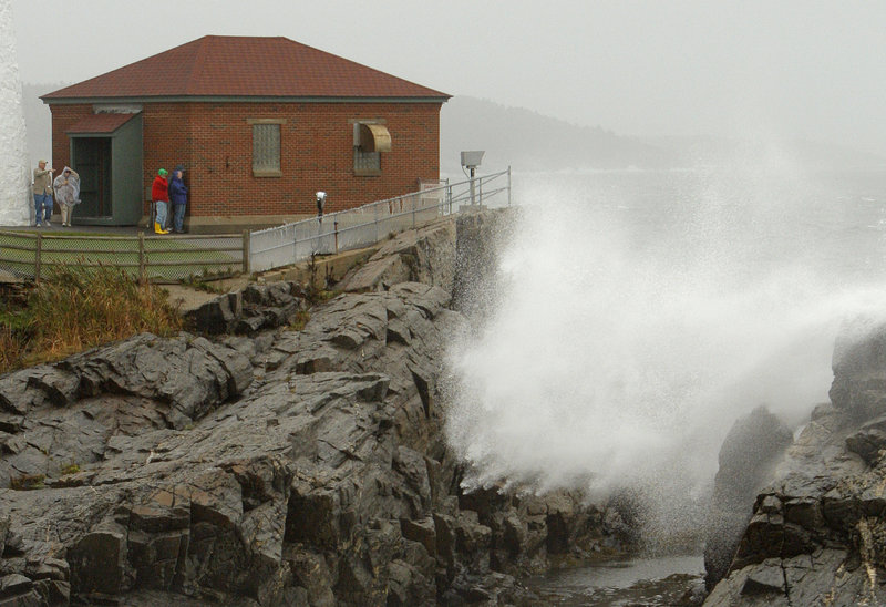 Spectators watch waves crash ashore at Portland Head Light in Cape Elizabeth during Friday’s nor’easter. Winds gusting to 50 mph downed trees and caused power outages, and leaf-clogged storm drains resulted in minor street flooding across southern Maine.