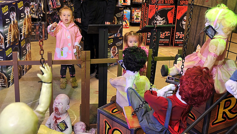The Charland sisters, Avery, 3, and 2-year-old Sophia, are a little leary of the Zombie Babies display at Spirit Halloween in South Portland on Friday. They were there with their mother, Jessica Charland, who said her daughters have asked for somewhat tamer costumes; Sophie wants to be a cupcake and Avery wants to be a princess.
