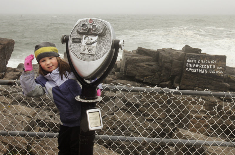 Jenna Bowie-Haskell, 4, of South Portland hangs on to a coin-operated viewer while checking out the surf Friday at Fort Williams Park with her father, Nick Bowie-Haskell.