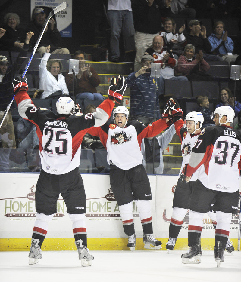 The Pirates celebrate after Dennis McCauley, center, scored Portland’s third goal with 2.6 seconds remaining in the second period. McCauley was assisted by Mark Mancari, left.