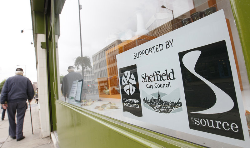 A man walks past an empty shop in a financially stalled redevelopment project in Sheffield, England, which now lets out shops left empty to local community artists.