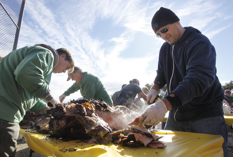 Matt Gallucci, right, a volunteer from Century 21 and Atlantic Realty, carves the ox roast with help from John Edmondson, left, a volunteer from the Stage Neck Inn.