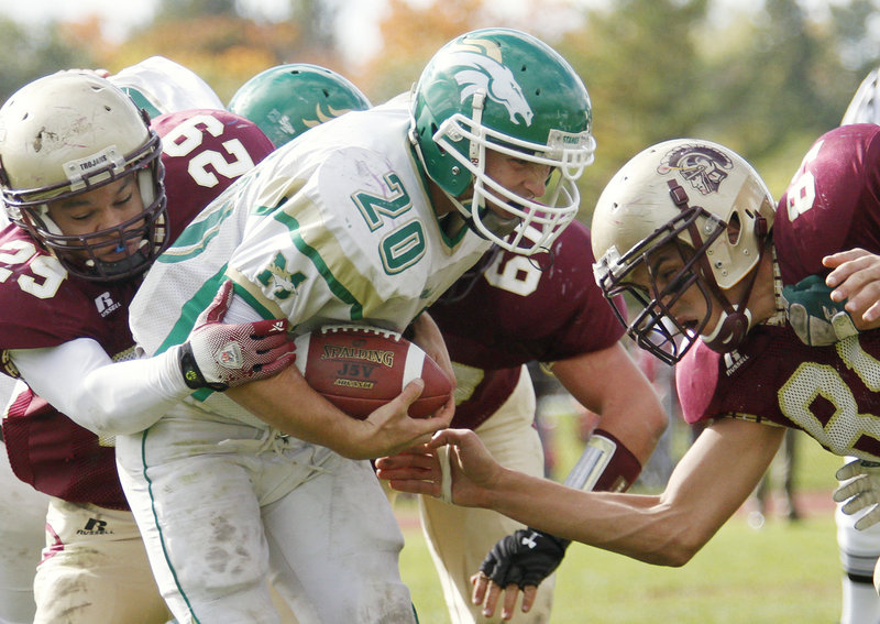 Casey Nava of Massabesic is stopped by Casey Wiseman, left, and Chris Dolewa of Thornton Academy during Thornton s 41-19 victory Saturday at Saco. The Golden Trojans improved to 6-1; Massabesic is 0-7.