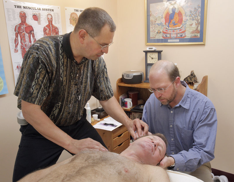 Reporter Ray Routhier, right, learns about massage therapy from Walter Selens in Portland. Selens has been a licensed massage therapist for 22 years.