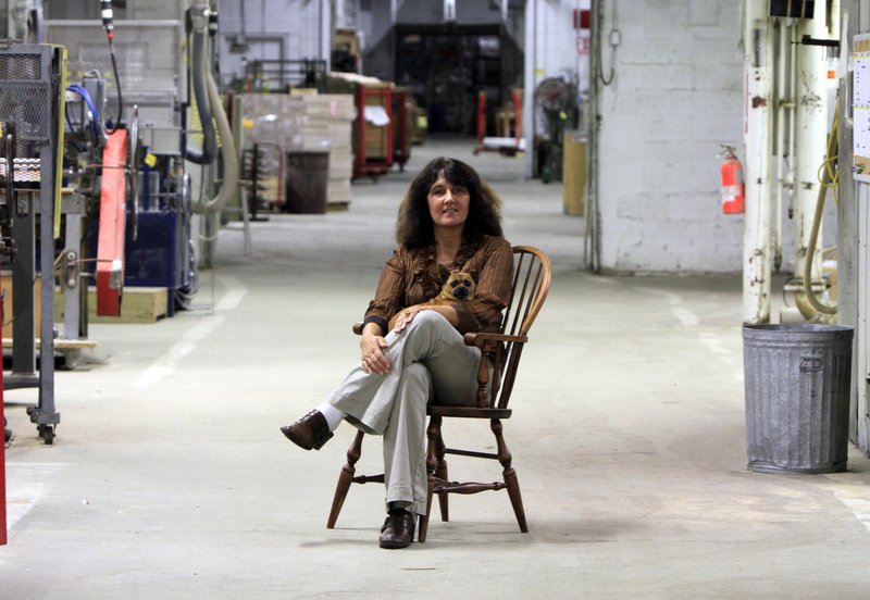 Louise Jonaitis and her dog Butterscotch sit in the recently reopened Saunders Bros. plant. Jonaitis has bought four mills saying that she intends to bring the plants back to life.