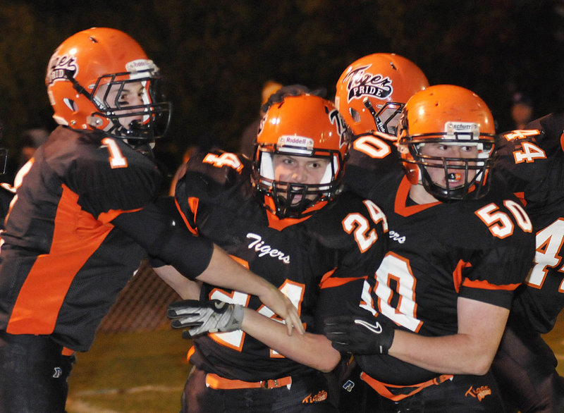 Patrick Wilson of Biddeford, center, is congratulated by J.D. Shannon, left, and Leonard Dube after scoring a first-period touchdown Friday night. The Tigers went on to beat Thornton Academy 27-22 in their rivalry game at Waterhouse Field.