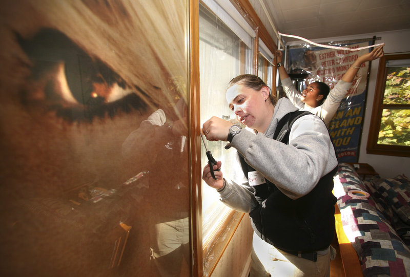 Eryn Kivo, left, a volunteer AmeriCorps NCCC worker from Minnesota, and Mercedes Porter, a volunteer AmeriCorps NCCC worker from California, weatherize a window at the home of Dick Dinman on Highland Avenue in Scarborough on Saturday.