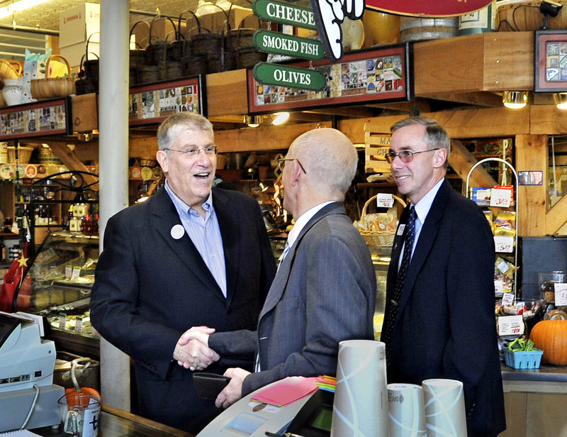 Eliot Cutler, left, greets a patron at the Public Market House on Monument Square as he makes the rounds Tuesday with Ed Suslovic, right, a former Portland mayor who’s running for the District 3 City Council seat.