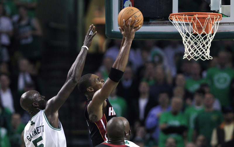 Chris Bosh of the Toronto Raptors slips past Kevin Garnett of the Boston Celtics for a layup Tuesday night. The Celtics opened the season with an 88-80 victory.