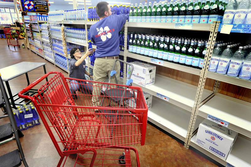 Marianna Reeves, squatting, and Steve Monks stock bottled water Wednesday at the Trader Joe’s store on Marginal Way in Portland. The store has been drawing fans and onlookers as it prepares for Friday’s grand opening.