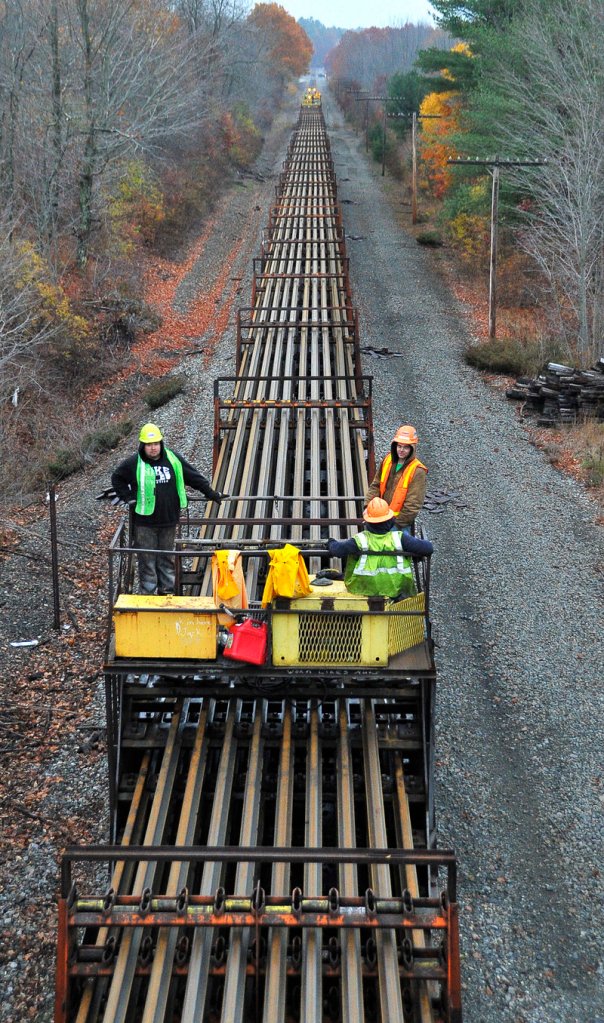 This crew, shown between Falmouth Road and Route 100 in Falmouth on Wednesday, will be responsible for depositing strings of welded rail line on each side of the bed for assembly in the spring.