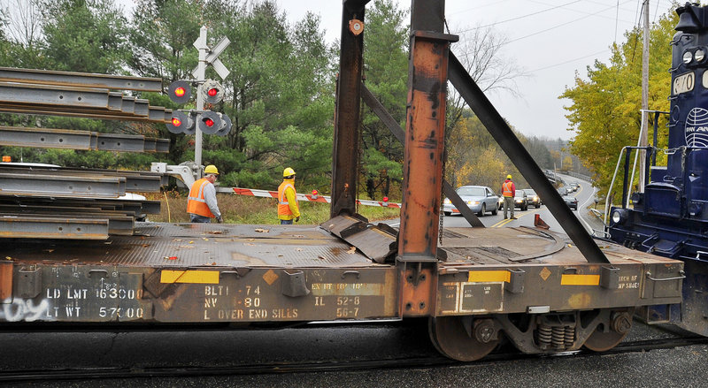 Traffic is stopped at the Leighton and Falmouth Road crossing in Falmouth for about 45 minutes Wednesday as rails are slipped off the back of a train in preparation for assembly in the spring.