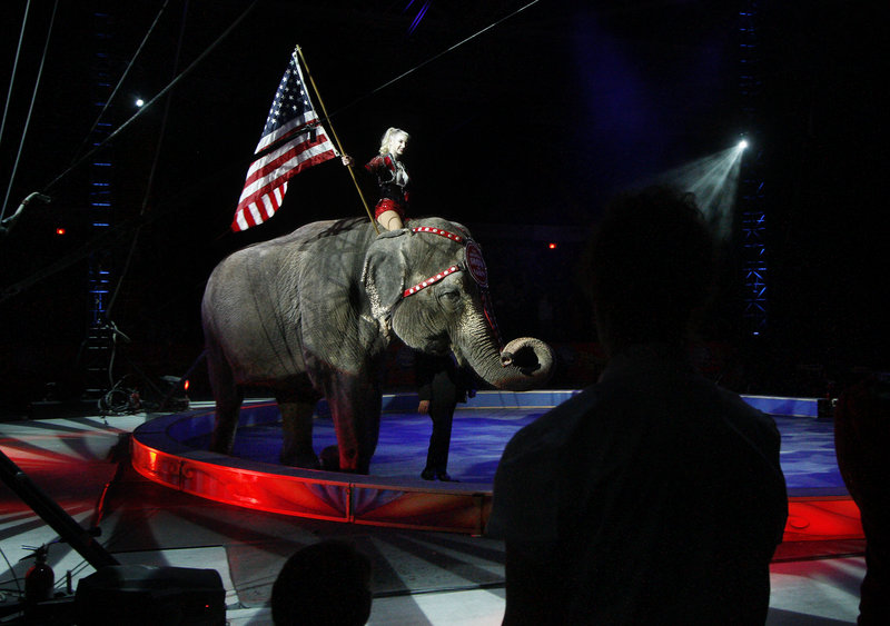 Performer Jamie Leigh carries the American flag atop one of the elephants during the opening night festivities.