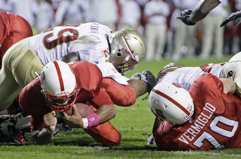 North Carolina State quarterback Russell Wilson dives past Florida State’s Kendall Smith, left, for a touchdown as Jake Vermiglio blocks during Thursday night’s game at Raleigh, N.C. Wilson ran for three scores in a 28-24 victory.