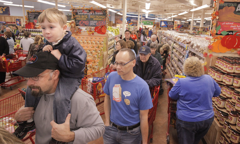Alex Hyfield, 3, sits on the shoulders of his father, Chris Hyfield, while they wait in one of the checkout lines at the new Trader Joe’s store in Portland on Friday. Throngs of Trader Joe’s devotees jammed the store for its grand opening.